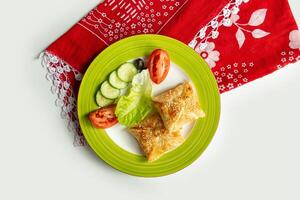 Turkish Peynirli Borek with cheese and salad in a dish isolated on colorful table cloth top view on grey background photo