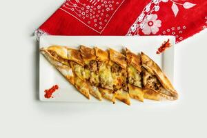 Turkish style Pide in a dish isolated on colorful table cloth top view on grey background in a dish isolated on colorful table cloth top view on grey background photo