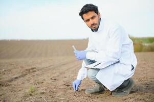 suelo pruebas. indio agronomía especialista tomando suelo muestra para Fertilidad análisis. manos en guantes cerca arriba. ambiental proteccion, orgánico suelo Certificación, campo trabajar, investigación foto