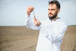 Agronomist studying samples of soil in field photo