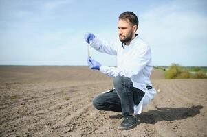 Agronomist studying samples of soil in field photo