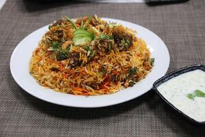 Kashmeri Lamb Biryani with raita served in a dish isolated on wooden background side view photo