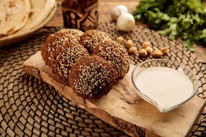 FALAFEL balls with raita served in a wooden board isolated on wooden table background side view of appetizer photo