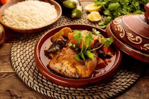 Moroccan Chicken and Vegetables Tangine with Couscous and bread served in a dish isolated on wooden background side view photo