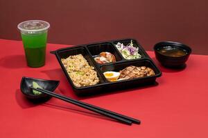 CHASUDON PREMIUM BENTO with mint margarita, sauce and chopsticks isolated on red background side view of japanese fast food photo