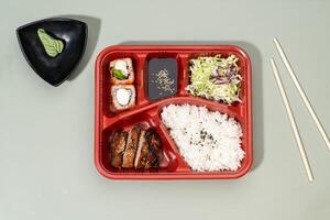 TORI TERIYAKI regular bento with drinks, rice and chopsticks isolated on grey background top view photo