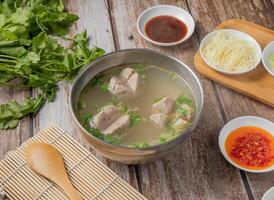 Gongwan soup or Gong wan pork balls meat soup with chilli sauce, noodles, spoon and chopsticks served in bowl isolated on napkin top view of hong kong food photo