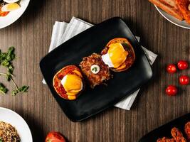 A healthy breakfast and fast food set of Eggs Blackstone, Wing Zing, Chicken Schnitzel Salad, Pan Fried Wild Cod Fish, Bratwurst Eggs Toast And Hasbrown with strawberry in dark wooden table top view. photo