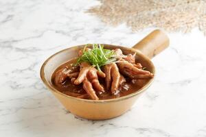 Stewed Chicken Claw in Abalone Sauce with chopsticks served in a dish isolated on grey background side view photo