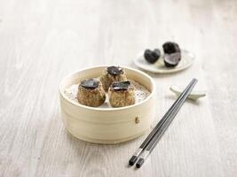 Steamed Beef Dumpling with Truffle served in a wooden bowl side view on grey marble background photo