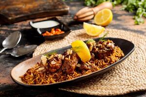 Machboos Hamour biryani rice with lime, raita and chilli sauce served in dish isolated on table top view of arabic breakfast photo