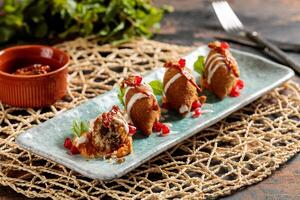 Kibbeh or kibe, quibe, kibbe with mayo dip, chilli sauce and pomegranate seeds served in dish isolated on table top view of arabic breakfast photo