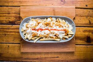Poutin fries loaded with mayo dip isolated on wooden board top view on table fastfood photo