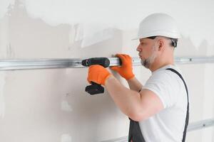 man fasten metal profile frame to the wall for draywall bulkhead. photo