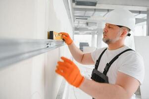 man fasten metal profile frame to the wall for draywall bulkhead. photo