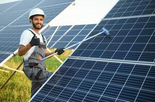 Indian handyman cleaning solar panels form dust and dirt. photo