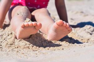 Close-up view of foots in the sands by the little girl on the sand beach,tropical summer vocations,holidays.A child enjoys the sea.Copy space.Close up.Soft focus. photo