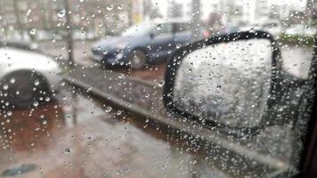 regendruppels Aan auto venster met wazig achtergrond van stad straten achtergrond Aan regenachtig dag in winter met spatten en druipend regendruppels kabbelend dramatisch in onweersbui en zwaar regen Aan auto venster video