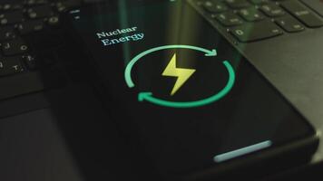 Nuclear Energy inscription on smartphone screen. Graphic presentation with Energy, Electricity, Power symbol on black background. Light rays. Power and Energy concept video