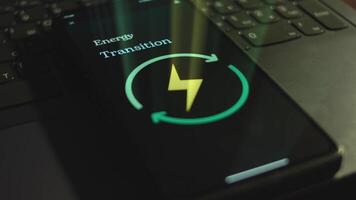 Energy Transition inscription on smartphone screen. Graphic presentation with Renewable Energy symbol on black background. Light rays. Power and Energy concept video