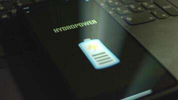 Hydropower inscription on smartphone screen. Graphic presentation of flickering battery symbol on black background. Light rays. Power and Energy concept video