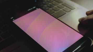 abstrakt bakgrund av ljus rosa vågor på smartphone skärm. strålar av ljus komma från skärm. manlig hand fladdrande med fingrar glatt video
