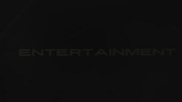 Entertainment news inscription of golden color on black background. Graphic presentation with dynamically moving spot and sparkles, festive atmosphere. Entertainment concept video