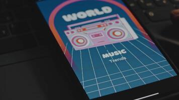 World music trends inscription on blue background. Graphic presentation with vintage cassette recorder drawing on smartphone screen. Male hands flapping fingers cheerfully. VHS effect video