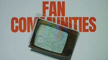 Fan communities inscription on grey background with image of a jumping vintage TV set, VHS effect on TV. Graphic presentation. Entertainment concept video