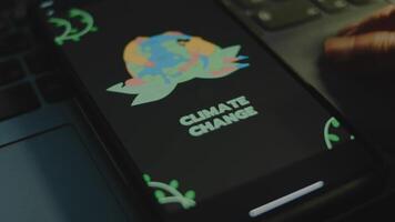 Climate change inscription on black background on smartphone screen. Drawn image of humans hugging Planet Earth. Environment concept. Male hand flapping fingers cheerfully video