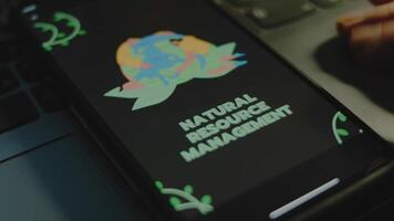 Natural resources management inscription on black background on smartphone screen. People protect Planet Earth image. Environment concept. Male hand flapping fingers cheerfully video