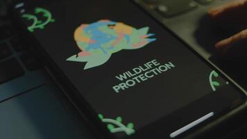 Wildlife protection inscription on smartphone screen. Drawn image of two people protecting Planet Earth. Environment concept. Male hand flapping fingers cheerfully video