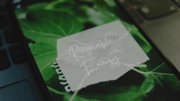 Renewable Energy inscription on smartphone screen. Graphic presentation with background of green leaves. Environment concept video