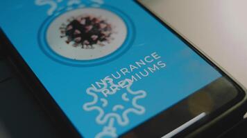 Insurance Premiums inscription on smartphone screen. Graphic presentation of a rotating virus cell. Healthcare and Medical Insurance concept video