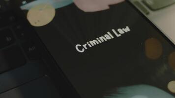 Criminal Law inscription on smartphone screen. Graphic presentation on black background with bokeh lights. Light rays. Legal concept video