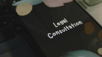 Legal Consultation inscription on smartphone screen. Graphic presentation on black background with bokeh lights. Light rays. Legal concept video