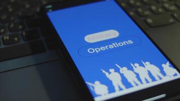 Military Operations inscription on smartphone screen with blue background, words in frames. Graphic presentation with silhouettes of soldiers with military equipment. Military concept video