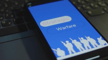 Strategic Warfare inscription on smartphone screen with blue background. Graphic presentation with silhouettes of soldiers with military equipment. Military concept video