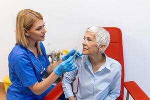 Female patient being tested for Covid-19 with a nasal swab, by a health Professional protected with gloves and PPE suit. Rapid Antigen Test during Coronavirus Pandemic. photo