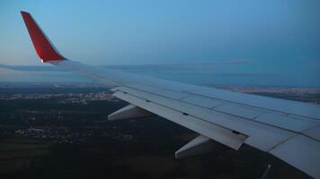 Flying over the city at dusk or dawn. Airplane wing, porthole. Airplane descent landing, first person view from the window video