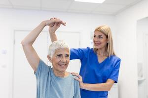 fisioterapeuta mujer dando ejercicio con pesa tratamiento acerca de brazo y hombro de mayor hembra paciente físico terapia concepto foto