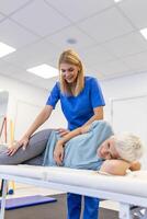 Professional chiropractor or physiotherapist helps to heal a senior woman's back. Doctor fixes the patient lying on a couch of a modern rehabilitation clinic Concept of physical rehabilitation. photo