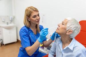 Doctor in a protective suit taking a throat and nasal swab from a patient to test for possible coronavirus infection photo