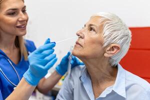 hembra paciente siendo probado para covid-19 con un nasal torunda, por un salud profesional protegido con guantes y ppe traje. rápido antígeno prueba durante coronavirus pandemia. foto