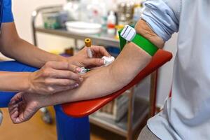 médico tecnólogo haciendo un sangre dibujar servicios para paciente. laboratorio asistente con estéril caucho guantes tomando sangre muestra desde paciente. foto