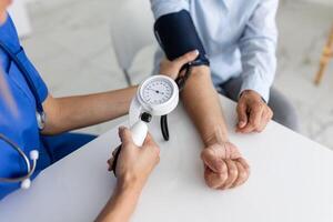 Doctor using sphygmomanometer with stethoscope checking blood pressure to a patient in the hospital. photo