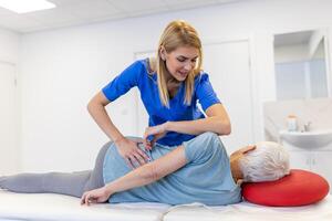 profesional quiropráctico o fisioterapeuta ayuda a sanar un mayor mujer atrás. médico arregla el paciente acostado en un sofá de un moderno rehabilitación clínica concepto de físico rehabilitación. foto