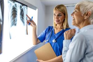 médico mujer comprobación radiografía película en médico laboratorio a hospital, explicando el resultados de escanear pulmón en pantalla a mayor paciente. foto