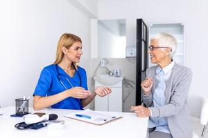 Senior woman, doctor and elderly patient with good news, tablet and results for health, advice and report. Happy medic, clipboard with smile, tech or support in hospital photo