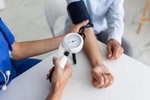 Doctor using sphygmomanometer with stethoscope checking blood pressure to a patient in the hospital. photo